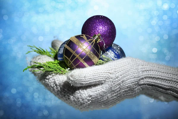 Female hands in mittens Christmas tree balls, on color background — Stock Photo, Image