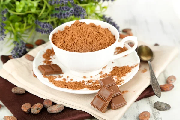 Cacao in polvere in tazza su tovagliolo su tavolo di legno — Foto Stock