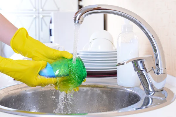 Закройте руки женщины, моющей посуду на кухне — стоковое фото