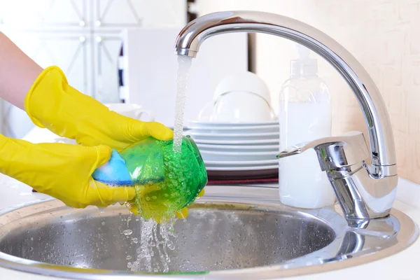 Fermer les mains de la femme qui lave la vaisselle dans la cuisine — Photo