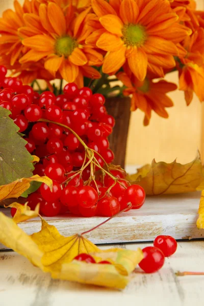 Baies rouges de viorne et vase avec des fleurs sur la table gros plan — Photo