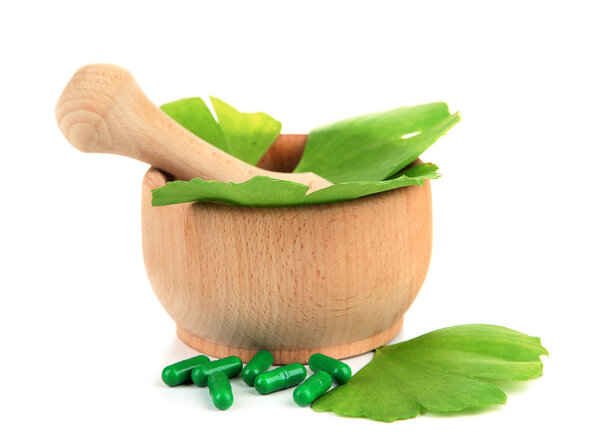 Ginkgo biloba leaves in mortar and pills isolated on white
