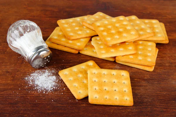 Deliziosi cracker con sale su sfondo di legno — Foto Stock
