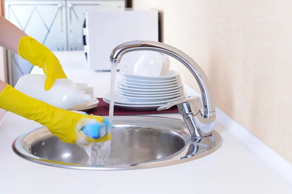 Fermer les mains de la femme qui lave la vaisselle dans la cuisine — Photo