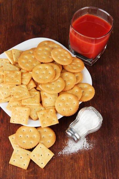 Deliziosi cracker con sale e succo di pomodoro su sfondo di legno — Foto Stock