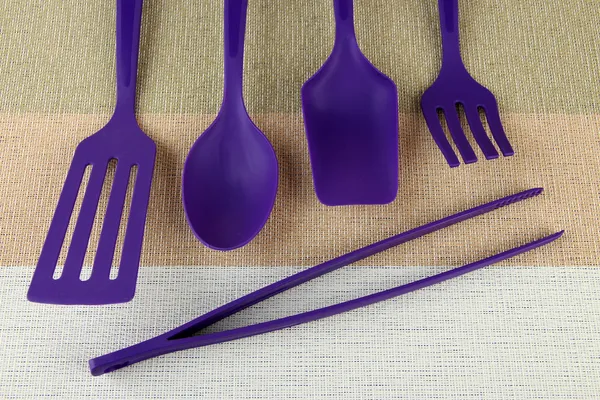 Plastic kitchen utensils on fabric background — Stock Photo, Image