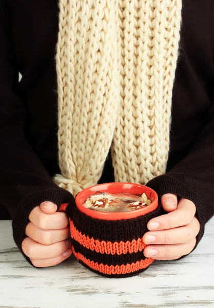 Cup with knitted thing on it in female hands close up — Stock Photo, Image