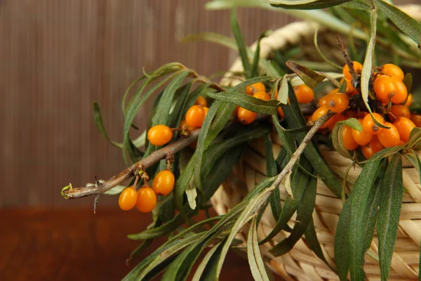 Branches of sea buckthorn in basket on table on bamboo background — Stock Photo, Image