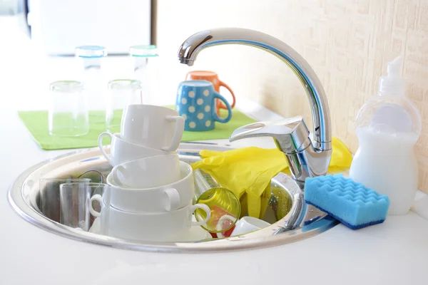 Stack of dishes soaking in kitchen sink — Stock Photo, Image