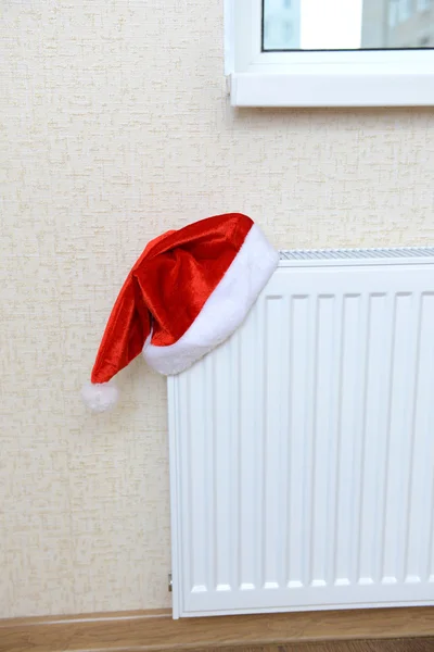 Red Christmas hat placed on white home heating radiator — Stock Photo, Image