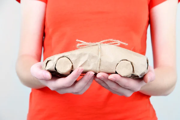 Mains de femme tenant une voiture enveloppée dans du papier kraft brun — Photo