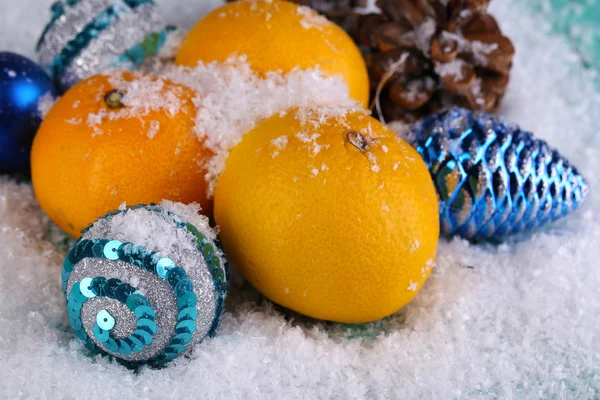 Tangerinas de Natal e brinquedos de Natal na mesa de madeira na neve — Fotografia de Stock