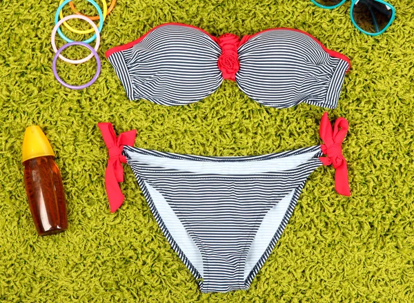 Swimsuit and beach items on green background — Stock Photo, Image