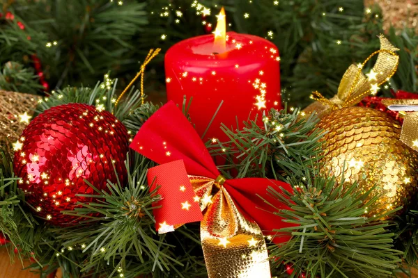 Composição de Natal com vela e decorações em cores vermelhas e douradas no fundo de madeira — Fotografia de Stock