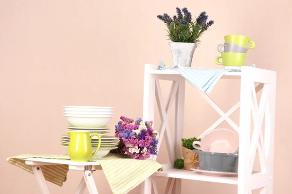 Красивые белые полки с посудой и декором, на фоне цветной стены — стоковое фото