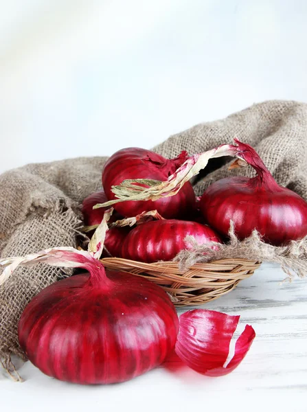 Cipolle rosse fresche in cesto di vimini sul tavolo da vicino — Foto Stock
