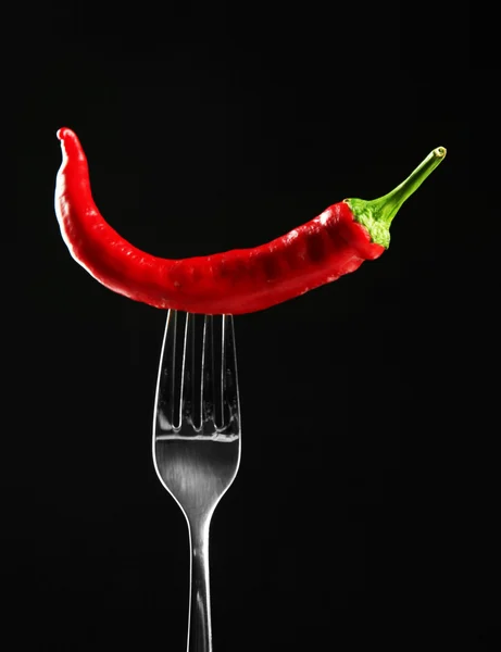 Red hot chili pepper on fork, isolated on black — Stock Photo, Image