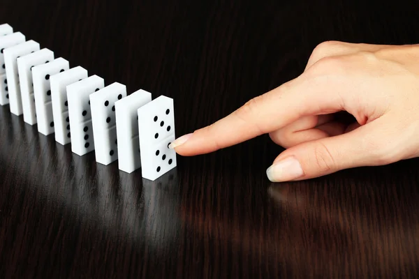 Hand pushing dominoes on wooden background — Stock Photo, Image