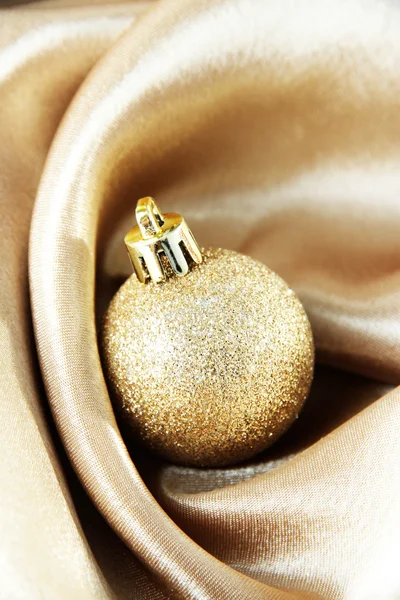Belle boule de Noël sur tissu satiné doré — Photo