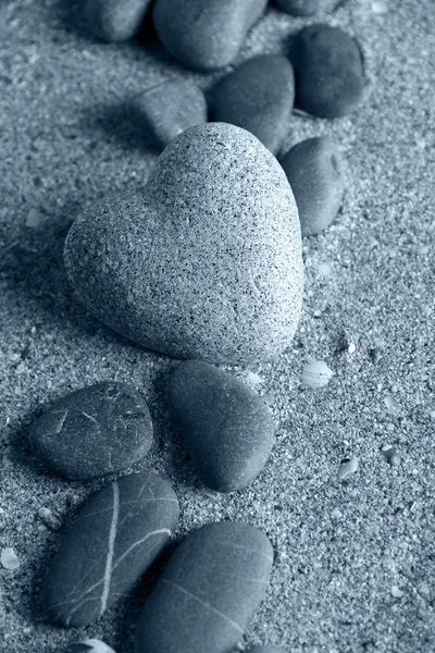 Grå sten i form av hjärta, på sand bakgrund — Stockfoto