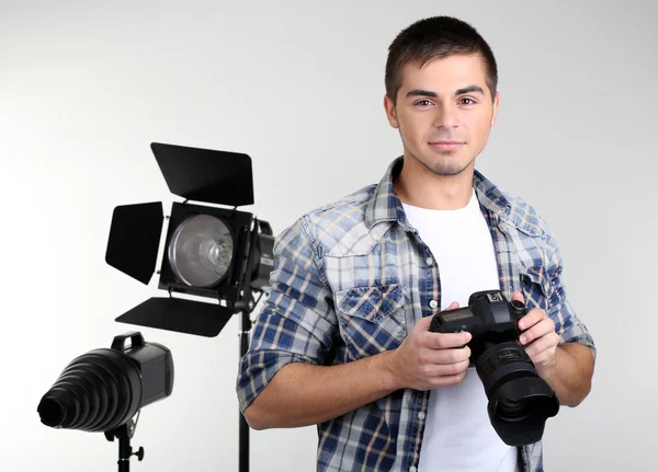 Schöner Fotograf mit Kamera, auf Studiohintergrund — Stockfoto