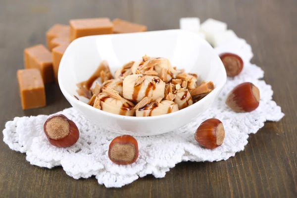 Many toffee in bowl on napkin on wooden table Stock Image