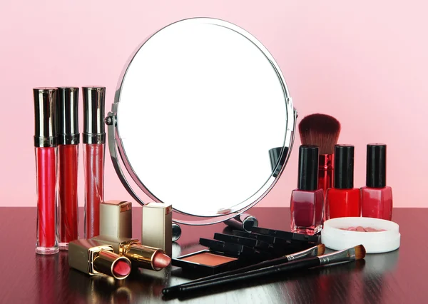 Kulatý stůl zrcadlo s kosmetikou na tabulce na růžovém pozadí — Stock fotografie