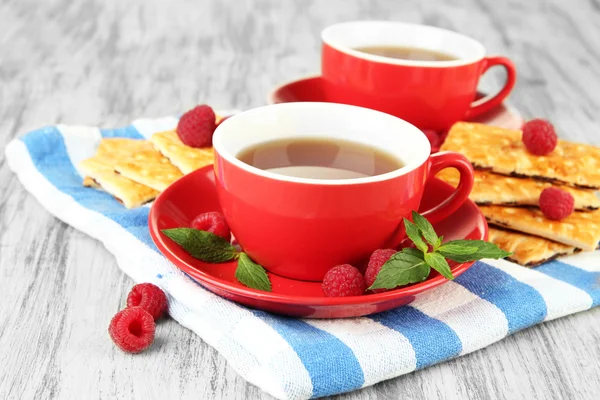 Чашки чая с печеньем и малиной на столе крупным планом — стоковое фото
