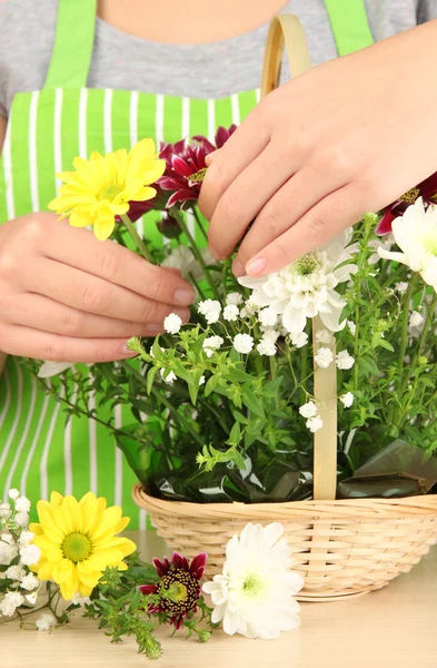 Florist makes flowers bouquet in wicker basket — Stock Photo, Image