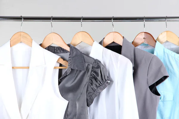 Офисная женская одежда на вешалках, на сером фоне — стоковое фото