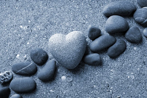 Grey stone in shape of heart, on sand background — Stock Photo, Image