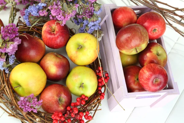 Saftige Äpfel in Schachtel auf weißem Holztisch — Stockfoto