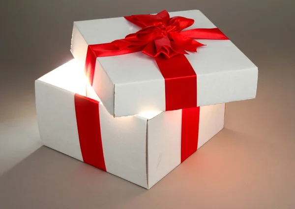 Geschenkbox mit hellem Licht auf grauem Hintergrund — Stockfoto