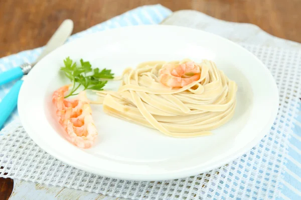 Pasta con gambas sobre plato blanco, sobre fondo de madera —  Fotos de Stock