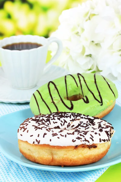 Søde donuts med kop te på bordet på lys baggrund - Stock-foto