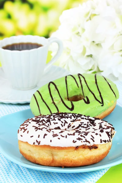 Rosquillas dulces con taza de té en la mesa sobre fondo brillante — Foto de Stock