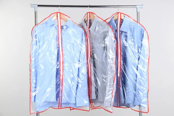 Office male clothes in cases for storing on hangers, on gray background — Stock Photo, Image