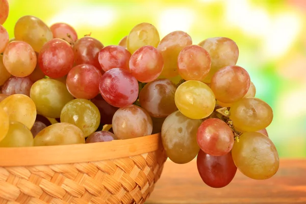 Ripe sweet grape in basket on wooden table, on nature background — Stock Photo, Image