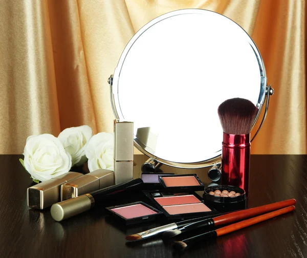 Round table mirror with cosmetics and flowers on table on fabric background — Stock Photo, Image