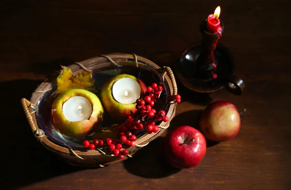 การประกอบด้วยแอปเปิ้ลและเทียนในตะกร้าบนพื้นหลังไม้ — ภาพถ่ายสต็อก