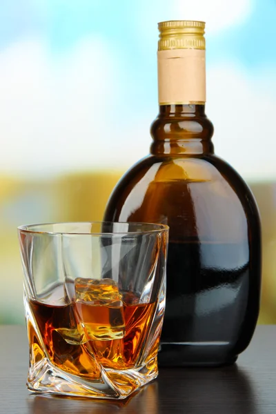 Glass of liquor with bottle, on dark background — Stock Photo, Image