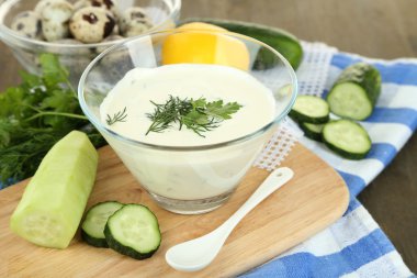 ahşap arka plan üzerinde renkli peçete üzerinde cam kase yoğurt salatalık