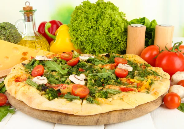 Tasty vegetarian pizza and vegetables on wooden table — Stock Photo, Image