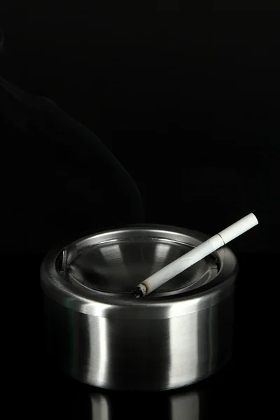 Cendrier en métal et cigarette sur fond noir — Photo
