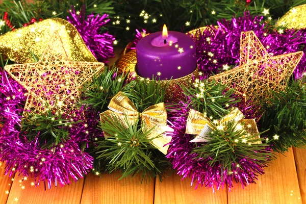 Новорічна композиція зі свічками та прикрасами в фіолетовому та золотому кольорах на дерев'яному фоні — стокове фото
