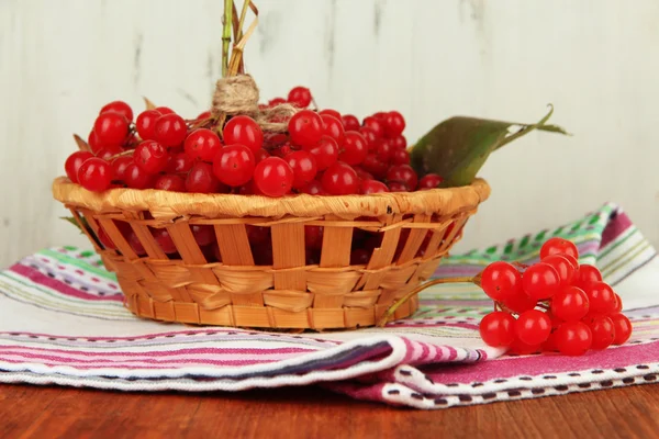 Bagas vermelhas de viburnum na cesta na mesa no fundo de madeira — Fotografia de Stock