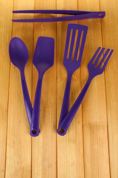 Plastic kitchen utensils on wooden background — Stock Photo, Image