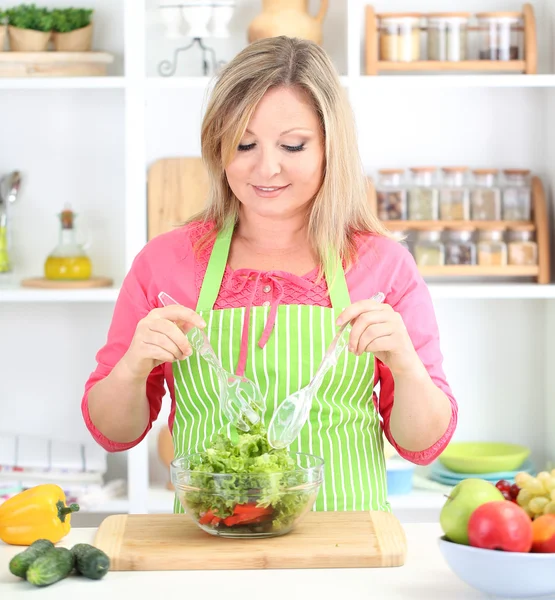 Mulher sorridente feliz na cozinha preparando salada vegetal — Fotografia de Stock