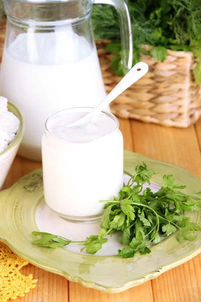 Produtos lácteos frescos com verduras na mesa de madeira em fundo natural — Fotografia de Stock