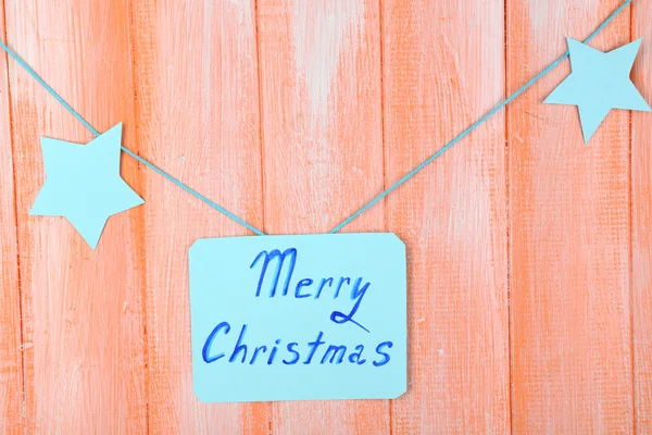 Schild mit den Worten Frohe Weihnachten auf orangefarbenem Holztischhintergrund Nahaufnahme — Stockfoto